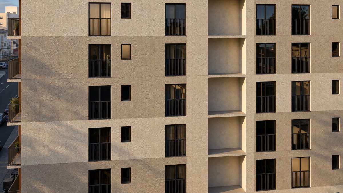 Detalhe da fachada do Sabiá Living: o reboco texturizado claro e as sacadas com guarda-corpo escuro