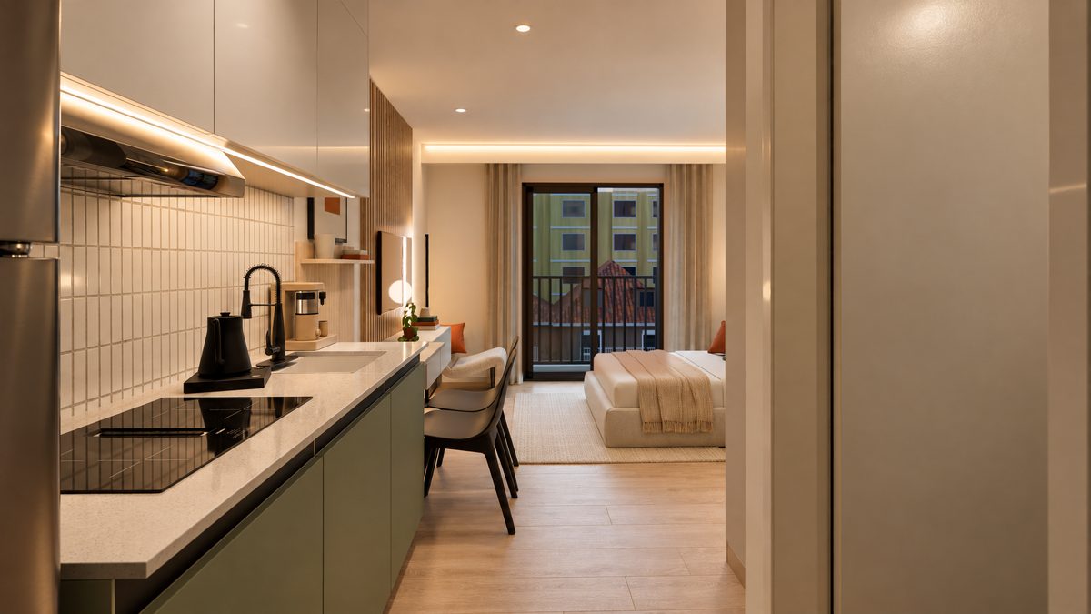 Studio tipo C: cozinha linear com cooktop e coifa, revestimento claro e, ao fundo, a cama junto à porta-janela